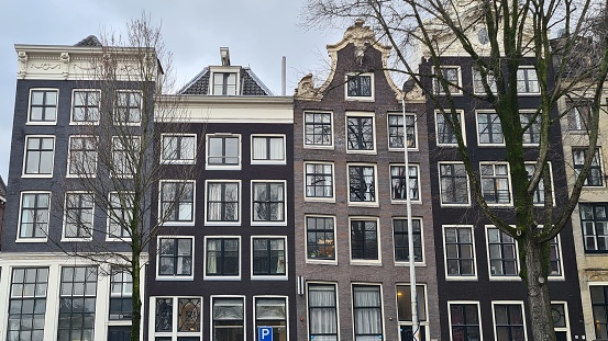 Amsterdam, Netherlands – March 21, 2023: Traditional houses of the 17th century in the downtown of Amsterdam.