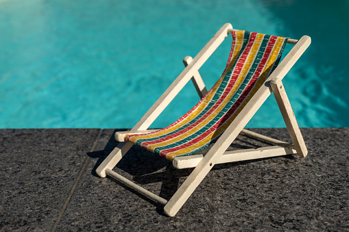 Aerial view of one deck chair, sunbed, lounge, flip flops on sandy beach. Summer and travel concept. Minimalism