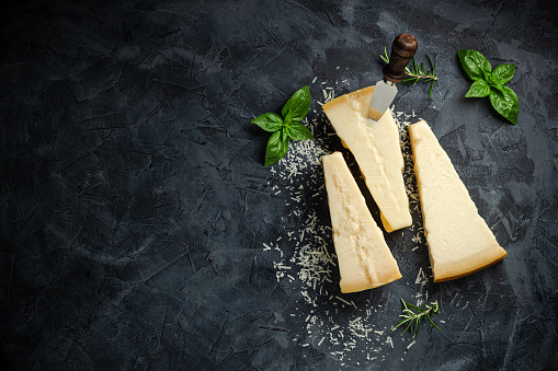 Hard cheese with basil on a dark background, Hard cheese, place for text top view.