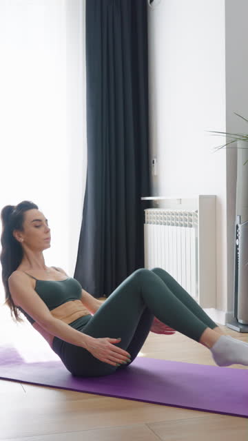 Vertical Screen: Woman doing abdominal exercises at home