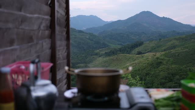 Blurred of Shabu Shabu Hot Pot on portable stove and food on wooden table with mountain views