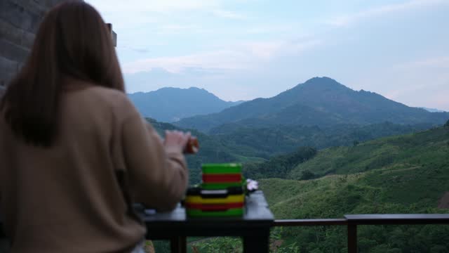 Blurred rear view of a woman preparing hot pot for dinner with evening sky and mountain views