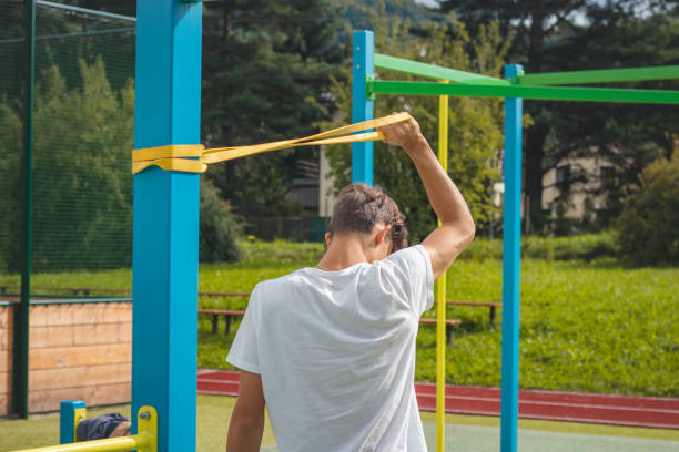 un adolescent axé sur les objectifs travaillant sur son corps à l’aide de caoutchouc de résistance effectue un entraînement en force. préparation de la saison sportive. faire de l’exercice avec votre propre corps. aire de jeux d’entraînement en - male torso abdominal muscle the human body photos et images de collection