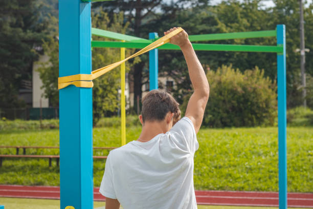 un adolescent axé sur les objectifs travaillant sur son corps à l’aide de caoutchouc de résistance effectue un entraînement en force. préparation de la saison sportive. faire de l’exercice avec votre propre corps. aire de jeux d’entraînement en - male torso abdominal muscle the human body photos et images de collection