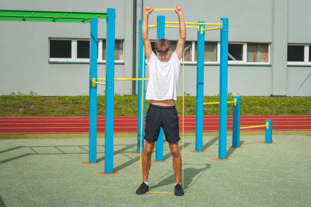 adolescent concentré travaillant sur son corps en utilisant du caoutchouc de résistance effectue un entraînement en force. préparation de la saison. faire de l’exercice avec votre propre corps. aire de jeux d’entraînement en plein air. haut du cor - male torso abdominal muscle the human body photos et images de collection