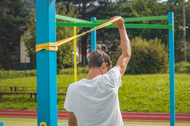 un adolescent axé sur les objectifs travaillant sur son corps à l’aide de caoutchouc de résistance effectue un entraînement en force. préparation de la saison sportive. faire de l’exercice avec votre propre corps. aire de jeux d’entraînement en - male torso abdominal muscle the human body photos et images de collection