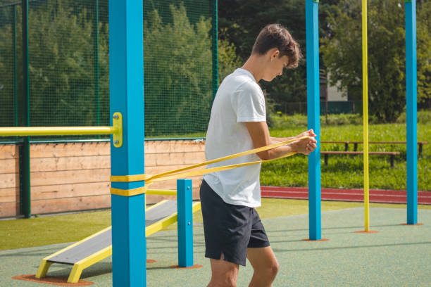 adolescent concentré travaillant sur son corps en utilisant du caoutchouc de résistance effectue un entraînement en force. préparation de la saison. faire de l’exercice avec votre propre corps. aire de jeux d’entraînement en plein air. muscles abd - male torso abdominal muscle the human body photos et images de collection