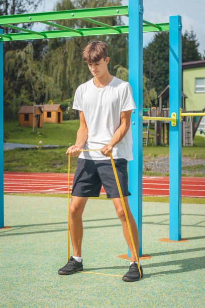 un adolescent axé sur les objectifs travaillant sur son corps à l’aide de caoutchouc de résistance effectue un entraînement en force. préparation de la saison sportive. faire de l’exercice avec votre propre corps. aire de jeux d’entraînement ex - male torso abdominal muscle the human body photos et images de collection