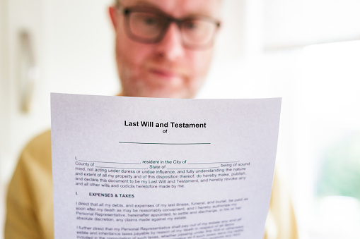 Portrait of a mid adult man reading a last will and testament document.