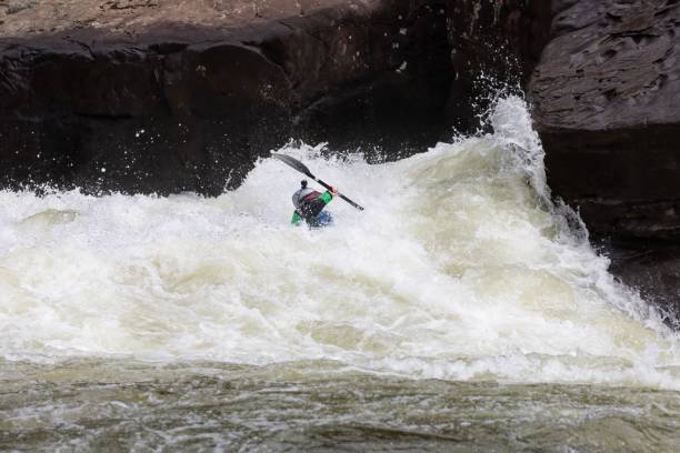 istock Man is kayaking in a raging river, surrounded by boulders. 1502313693