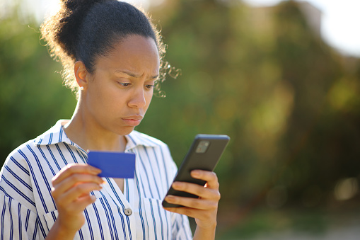 Worried black online buyer checking phone
