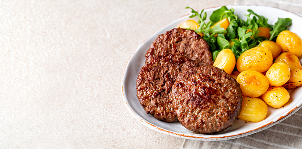 Banner with homemade dinner. Meat patties with baked potatoes and salad, mayonnaise. Beef Cutlets, burgers or hamburger. Copy space.