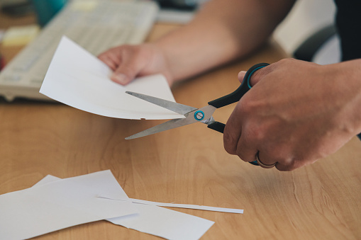 Left-handed man's hand cutting paper with scissors