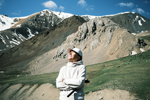 Portrait of mature female backpacker looking around in beautiful gorge of Tien Shan