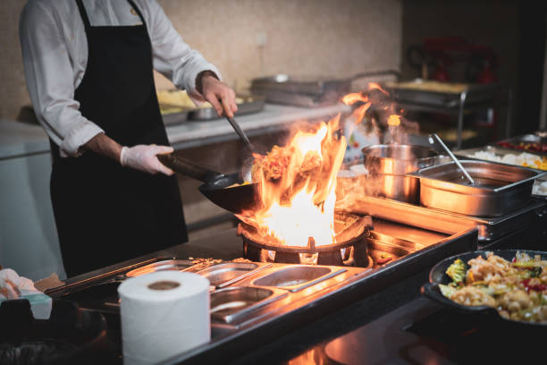 istock Chef cooks with fire in a pan shrimp with vegetables 1502328441