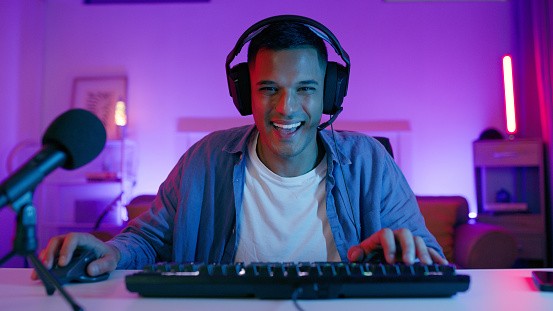 Happy, gaming and portrait of man with keyboard for esports, video games and virtual competition. Neon, computer and male gamer with headphones for playing cyber, rpg and online game on PC at desk