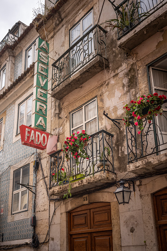 Lisbon, Portugal - May 25, 2022: Classic facade of a house in Lisbon Portugal with old neon sign and decorated balconies.