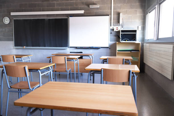 istock Empty high school classroom with natural light. Wooden desks and chairs, blackboard and whiteboard. Education. 1502341495