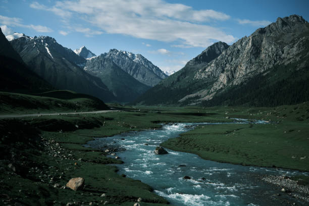 istock River flowing on green valley towards mountain peaks 1502343923