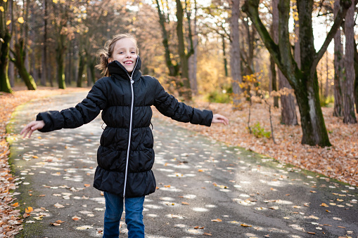 Happy girl running in autumn park and looking at camera