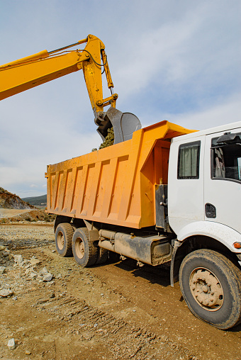 The excavator loads rocks onto the mining dump truck in the quarry area.