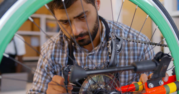 istock Male mechanic repair customer bicycle wheel in workshop 1502382525
