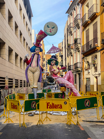 Valencia, Spain - March 3, 2023: Barricaded street with a Ninot in the middle of it. This are huge dolls that are built specifically to be burnt during the last night of Las Fallas annual event, exclusive to the Valencian Community