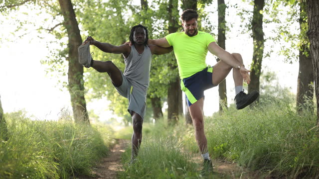 Young male friends stretching before jogging in nature