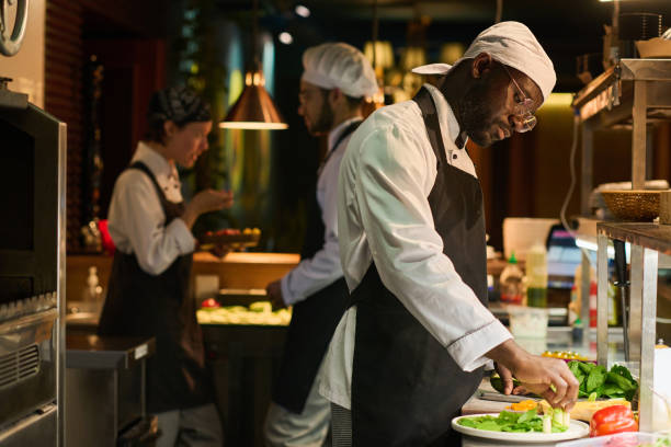 istock Young serious chef of restaurant mixing fresh chopped vegetables 1502384658