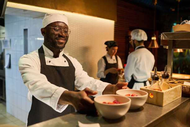 istock Happy young male chef in uniform taking two bowls with ingredients 1502384662