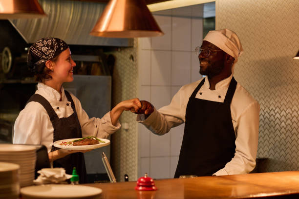 istock Two happy young intercultural kitchen workers giving each other punch bump 1502384725