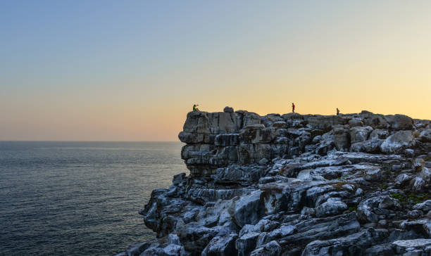 podróżnik stojący na skale - sunrise beach couple hiking zdjęcia i obrazy z banku zdjęć