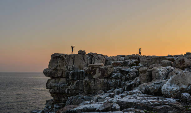 podróżnik stojący na skale - sunrise beach couple hiking zdjęcia i obrazy z banku zdjęć