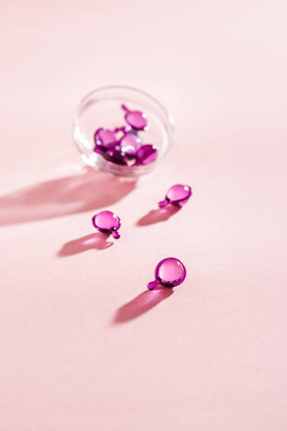витаминные капсулы розового, фиолетового цвета, крупный план на розовом фоне, вид сверху - spa treatment capsule body care hair gel стоковые фото и изображения