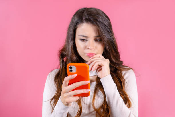 istock Lady looks deep thinking and holding mobile phone on the pink backgtound 1502403574