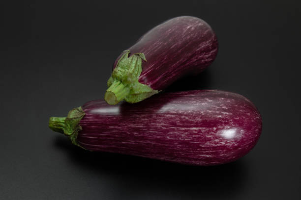 istock Two striped purple Graffiti or Fairy Tale eggplants on dark surface 1502407357