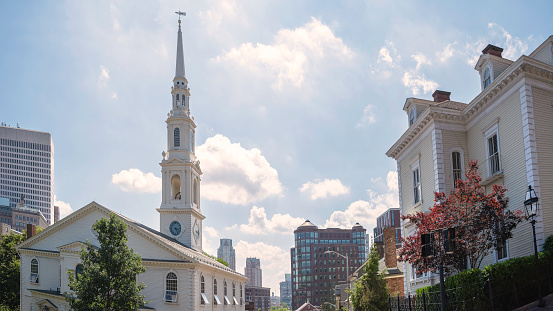 Providence city skyline with a church, commercial buildings, and bright summer's sky and white clouds in Rhode island