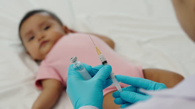 doctor drawing syringe and preparing vaccine giving injection to infant baby