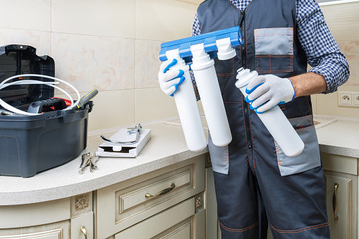 Plumber installing or repairing system of water filtration. Water purification filter install. Concept clean water.