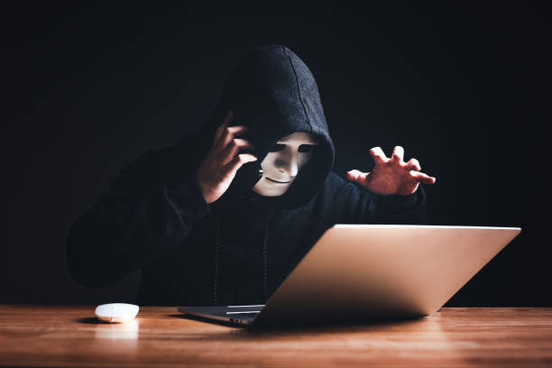 istock Black hat hacker in hood using laptop computer and call smartphone to victim on desk hacking privacy sensitive data hack in dark room background. Cyber security cyber crime concept. Hacking phishing 1502418572