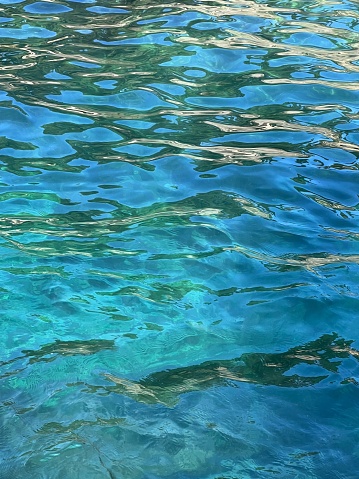 Sea waves blue turquoise glittering clear ripples surface.