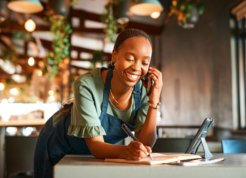 Phone call, restaurant or happy woman writing order as a small business owner, entrepreneur or waitress. Cafe, smile or barista talking, listening or taking orders in notebook, diary or telephone