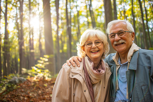 Active senior couple enjoying walk in the woods. They are looking at the camera