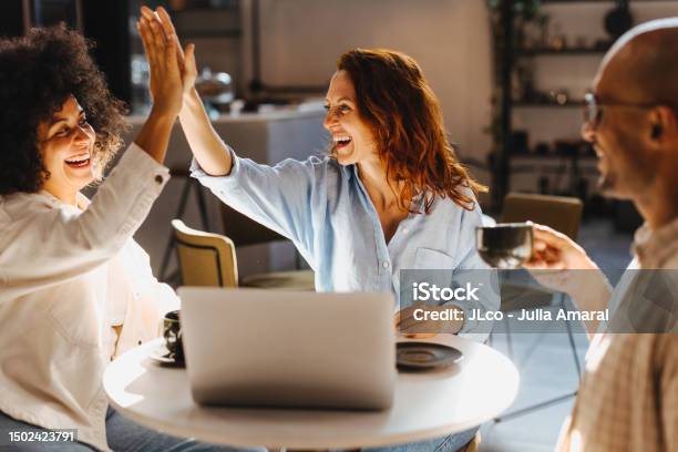 Successful Business Team High Fiving In A Coffee Shop Stock Photo - Download Image Now