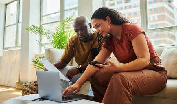 istock A young interracial couple using their laptop computer and mobile phone to work on their budget and finances from home. 1502425279