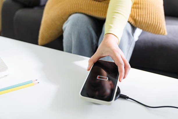 istock Woman hands plugging a charger in a smart phone. Charging Smartphone with Wireless Charging Pad at Home 1502425345