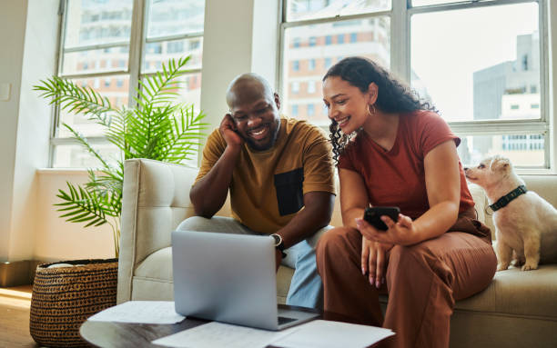 istock A young couple sitting on the couch working on their finances with a laptop computer looking at each other while smiling. stock photo, copy space 1502425450