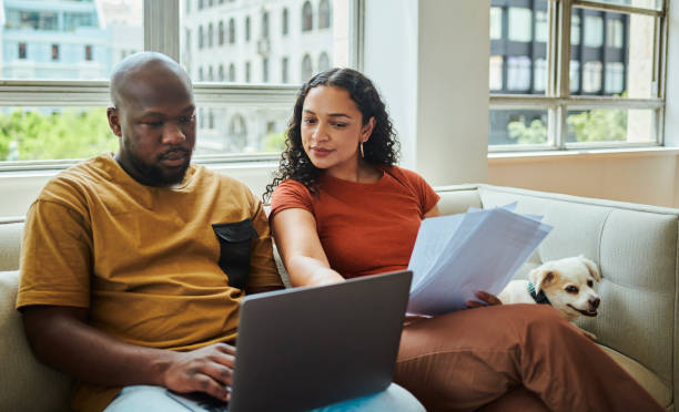 istock A young interracial couple working on their budget and finances on a sofa from home with their dog using a laptop computer, stock photo 1502425535