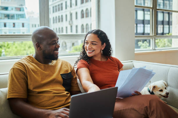 istock A young happy interracial couple working on their budget and finances on a sofa from home with their dog using a laptop computer, stock photo 1502425606