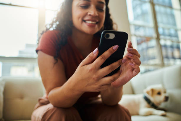 istock A young woman sitting on her sofa with her dog while smiling and texting on her mobile phone. Stock photo 1502425709